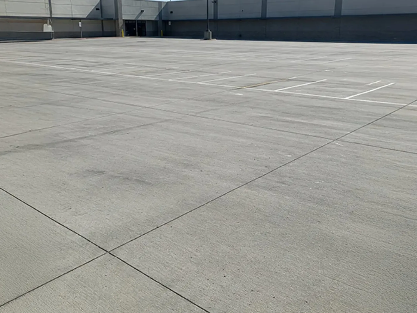 Broom finished commercial concrete parking area with painted white stall lines in front of a building