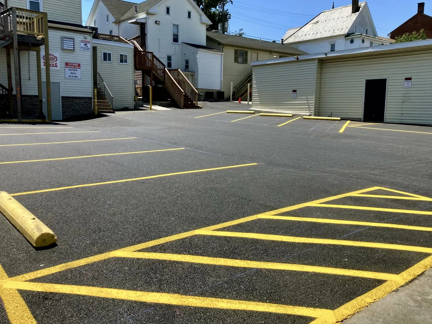 Freshly striped parking stalls and a hatched no-parking zone in yellow on black asphalt