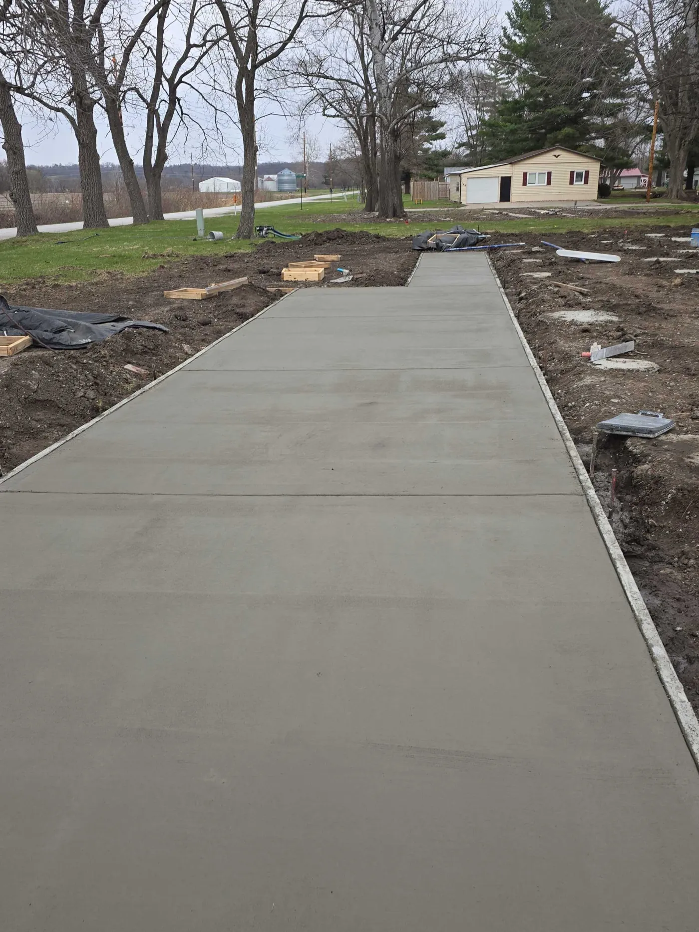 Long run of new concrete sidewalk curing along a residential street